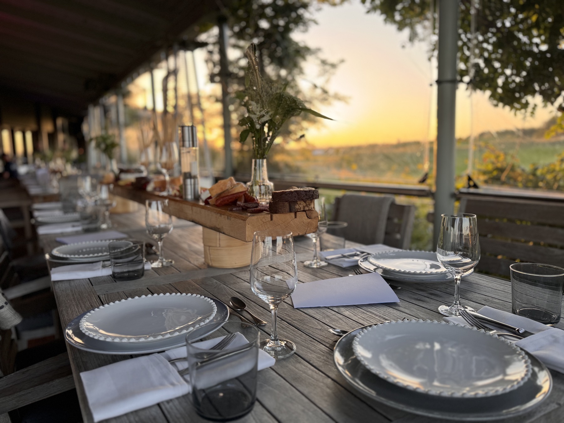 Festlich gedeckte Terrasse eines Golfclubs mit Blick über den Platz bei Sonnenuntergang